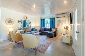 A modern living room with a sofa, armchairs, a coffee table, and a TV.
