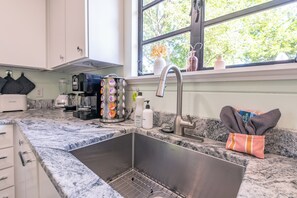 A kitchen with a stainless steel sink, a coffee maker, and a dish soap bottle.