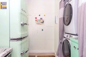 A laundry room with a washing machine, dryer, and a bulletin board with a poster. - Lustrous Lustron (Bloomington)
