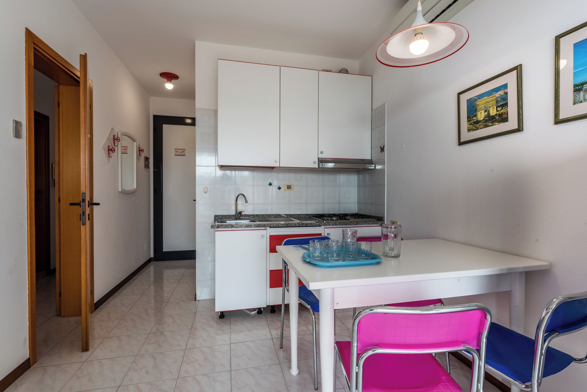 A compact kitchen with white cabinets, a gas stove, a sink, and a dining table with chairs.