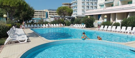 A swimming pool with lounge chairs and a building in the background.