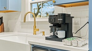 A modern kitchen with a coffee maker, a sink, and a window with a view of trees.