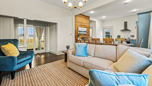 A modern living room with a blue armchair, beige sofa, and patterned rug.