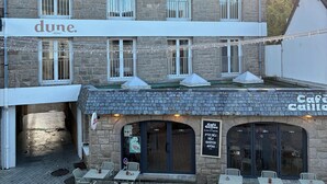 A hotel with a stone facade, multiple windows, and outdoor seating area. - DUNE (Saint-Pierre-Quiberon)