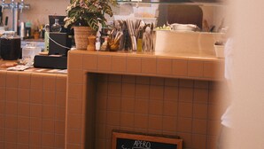 A restaurant interior with a menu board, hanging lights, and a tiled wall. - DUNE (Saint-Pierre-Quiberon)