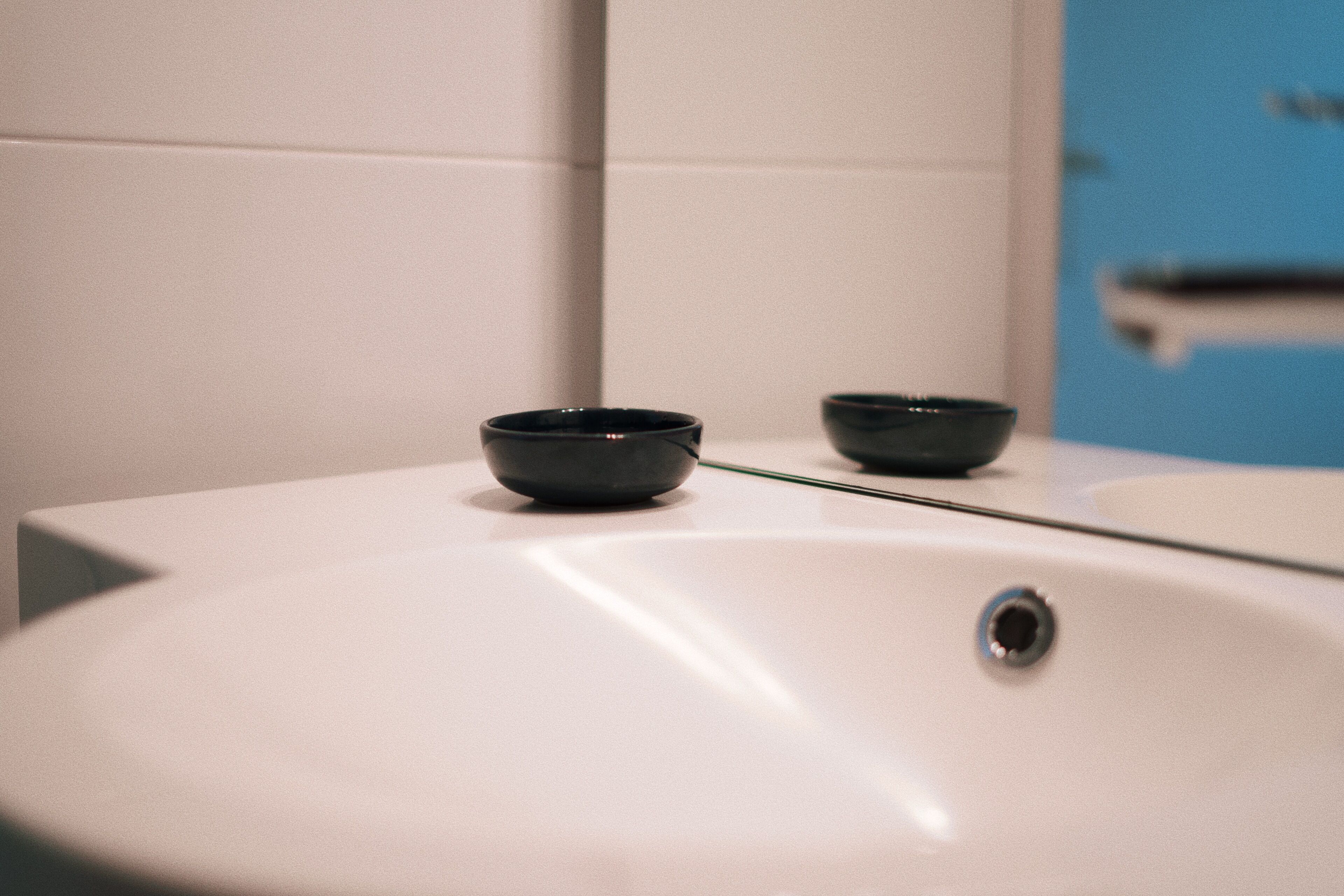 A bathroom with a white sink and two black bowls on the counter.
