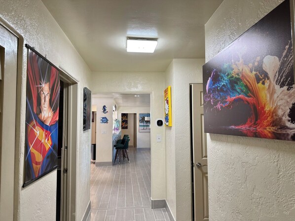 A hallway with artwork on the walls, a ceiling light, and a door at the end. - Luxury Waterfront Retreat near Daytona Beach (Daytona Beach)