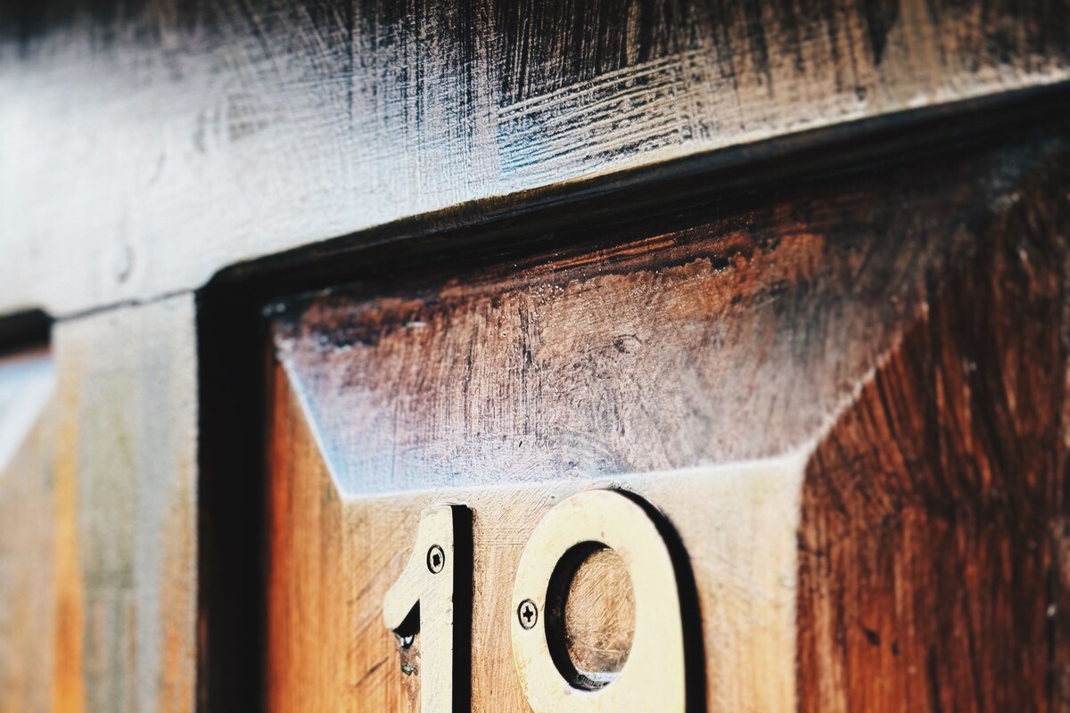 A wooden door with a brass number plate displaying the number 19.