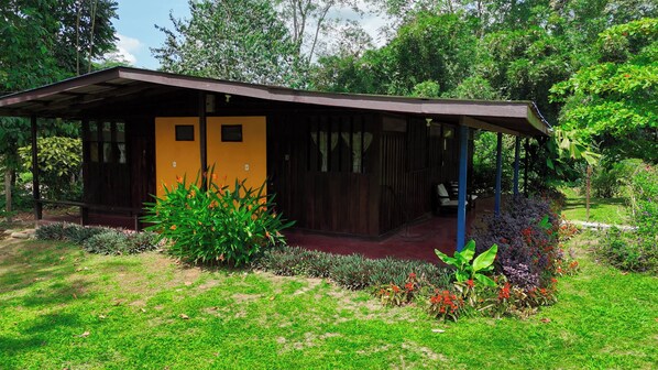 A single-story building with a sloped roof, a porch, and a small garden area with various plants and flowers. - Gran Gavilan del Sarapiqui Lodge   (Puerto Viejo)