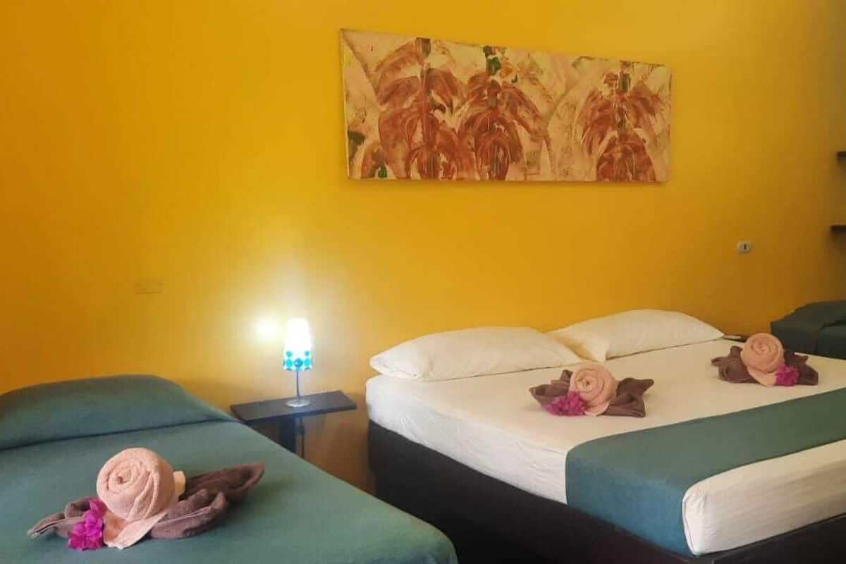 A hotel room with two beds, a nightstand with a lamp, and a painting on the wall.