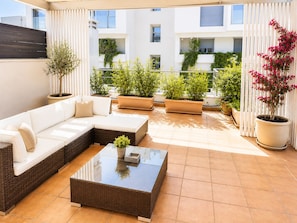 A sunlit outdoor seating area with a sofa, a coffee table, and potted plants. - Adelos II Glow Villa 5BR 360m² -elevator-rooftop (Elliniko-Argyroupoli)