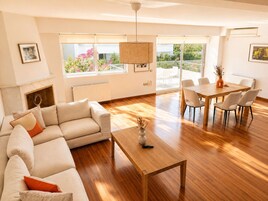 Una sala de estar moderna con un sofá, una mesa de centro de madera y un comedor con sillas y una mesa.