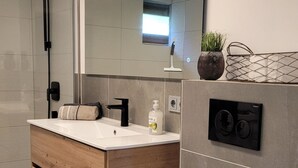A modern bathroom with a wooden vanity, a white toilet, a large mirror, and a shower area. - Apartment Schöne Schwarzwald Auszeit in the hiking paradise with its own terrace (Friedenweiler)