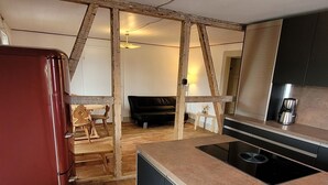 A compact kitchen with wooden flooring, a built-in stove, and a refrigerator. - Apartment Schöne Schwarzwald Auszeit in the hiking paradise with its own terrace (Friedenweiler)