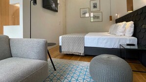 A modern bedroom with a bed, two chairs, a floor lamp, and framed pictures on the wall. - Studio.Ø4 Garden View (Porto)