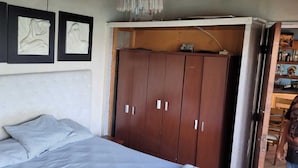 Een slaapkamer met een bed, een kledingkast en drie sculpturen aan de muur.