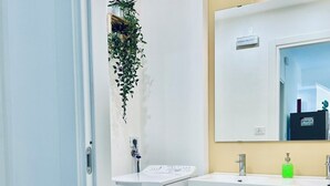 Une salle de bain moderne avec un lavabo blanc, un miroir et une petite plante suspendue au mur.