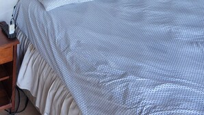 Une chambre à coucher comprenant un lit, une table de chevet et trois sculptures fixées au mur.