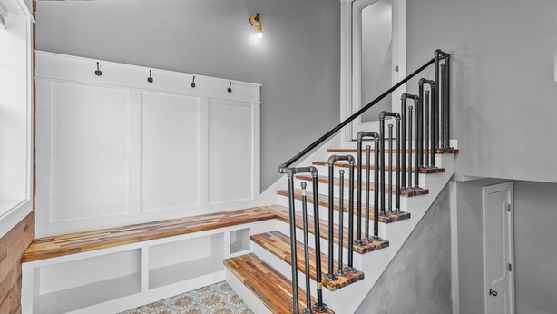 A staircase with wooden steps and metal railings, a bench with storage cabinets, and a patterned floor.