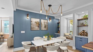 A dining area with a white table and chairs, blue walls, and a chandelier.