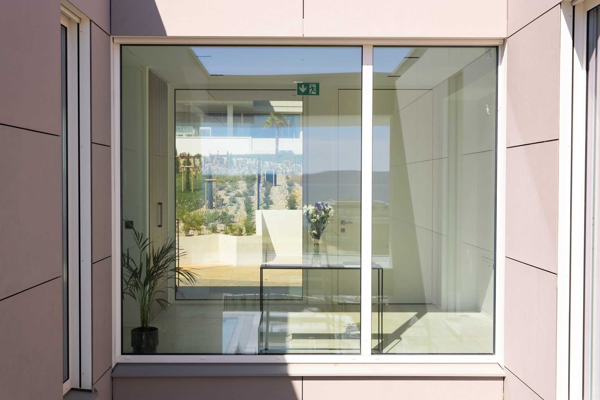 A modern building with a large glass window, a potted plant, and a view of a cityscape.