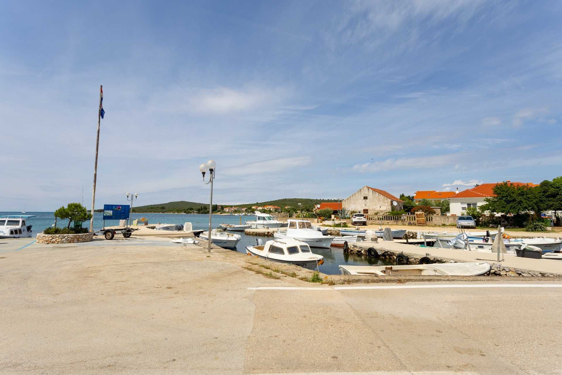A marina with boats docked, a flagpole, and buildings in the background.