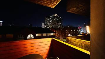 A nighttime view from a rooftop with a cityscape in the background, featuring a prominent illuminated building.