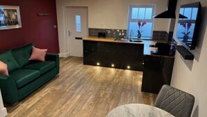 Een moderne keuken met een centraal eiland, een eethoek met een ronde tafel, en een groene bank.