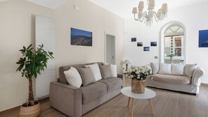 A modern living room with a grey sofa, a striped sofa, a round table, and a chandelier.