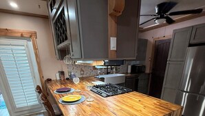 A kitchen with a wooden island, stainless steel appliances, and a dining area with chairs. - Midtown Cottage, unique stone patio, family-dog friendly newly remodeled. (Tulsa)