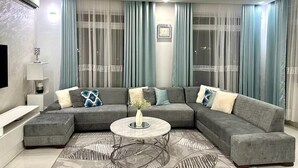Ein modernes Wohnzimmer mit einem Ecksofa, einem Couchtisch und einem Deckenventilator.