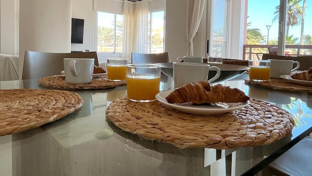 Taula de l'esmorzar amb sovinadors teixits, croissants i vasos de suc d'aranja.