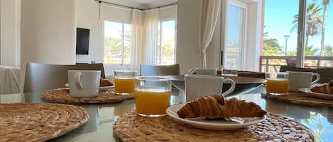 Une table de petit-déjeuner avec des sets de table en fibres tressées, des croissants et des verres de jus d’orange.