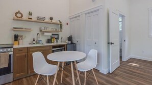 Moderni keittiö, jossa on puiset kaapit, sisäänrakennettu uuni ja ruokailutila, jossa on kaksi valkoista tuolia.