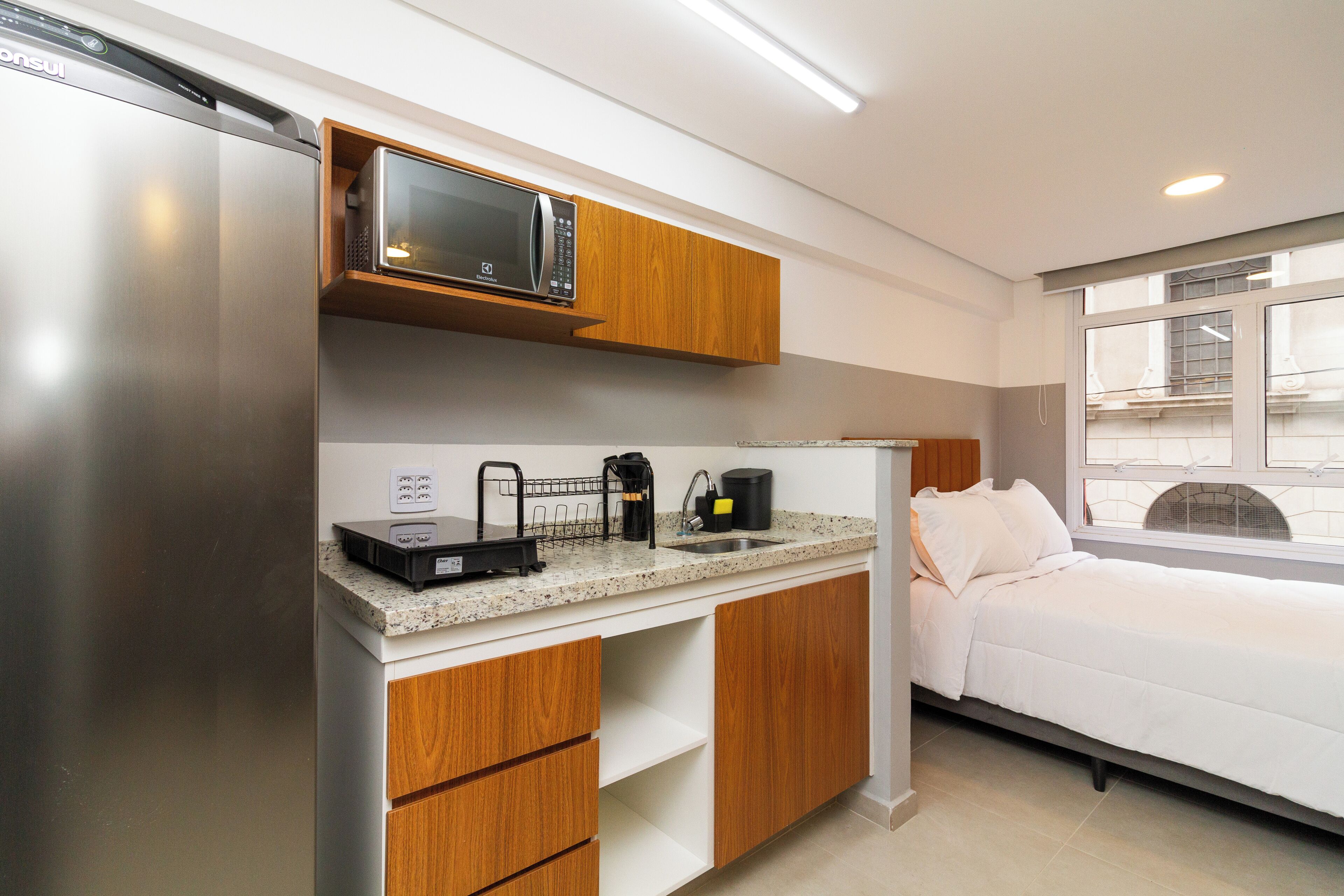 A compact kitchen with a microwave, coffee maker, and a small sink.