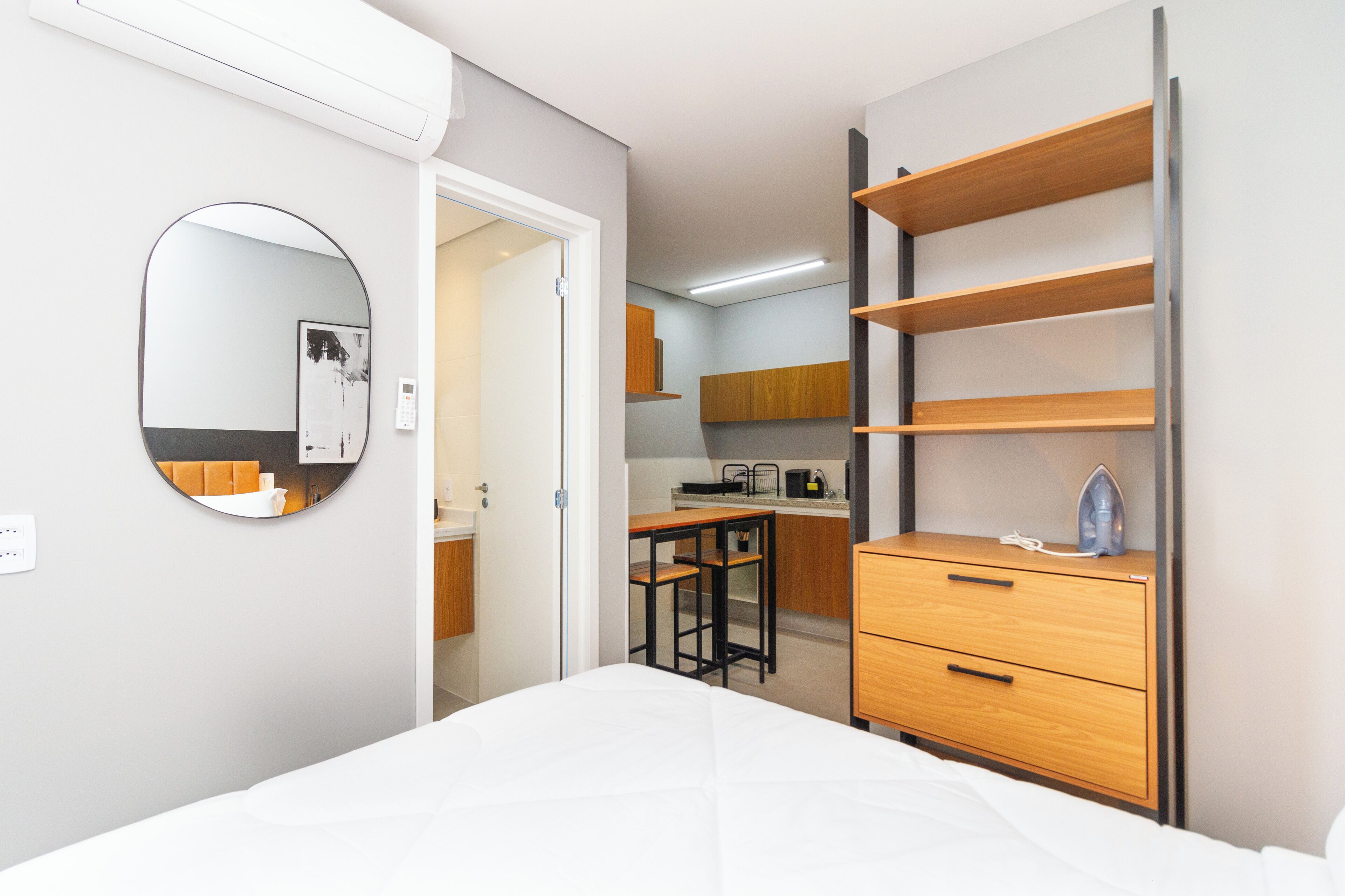 Habitació petita i funcional amb llit, taula de nit, mirall i armari encastrat.