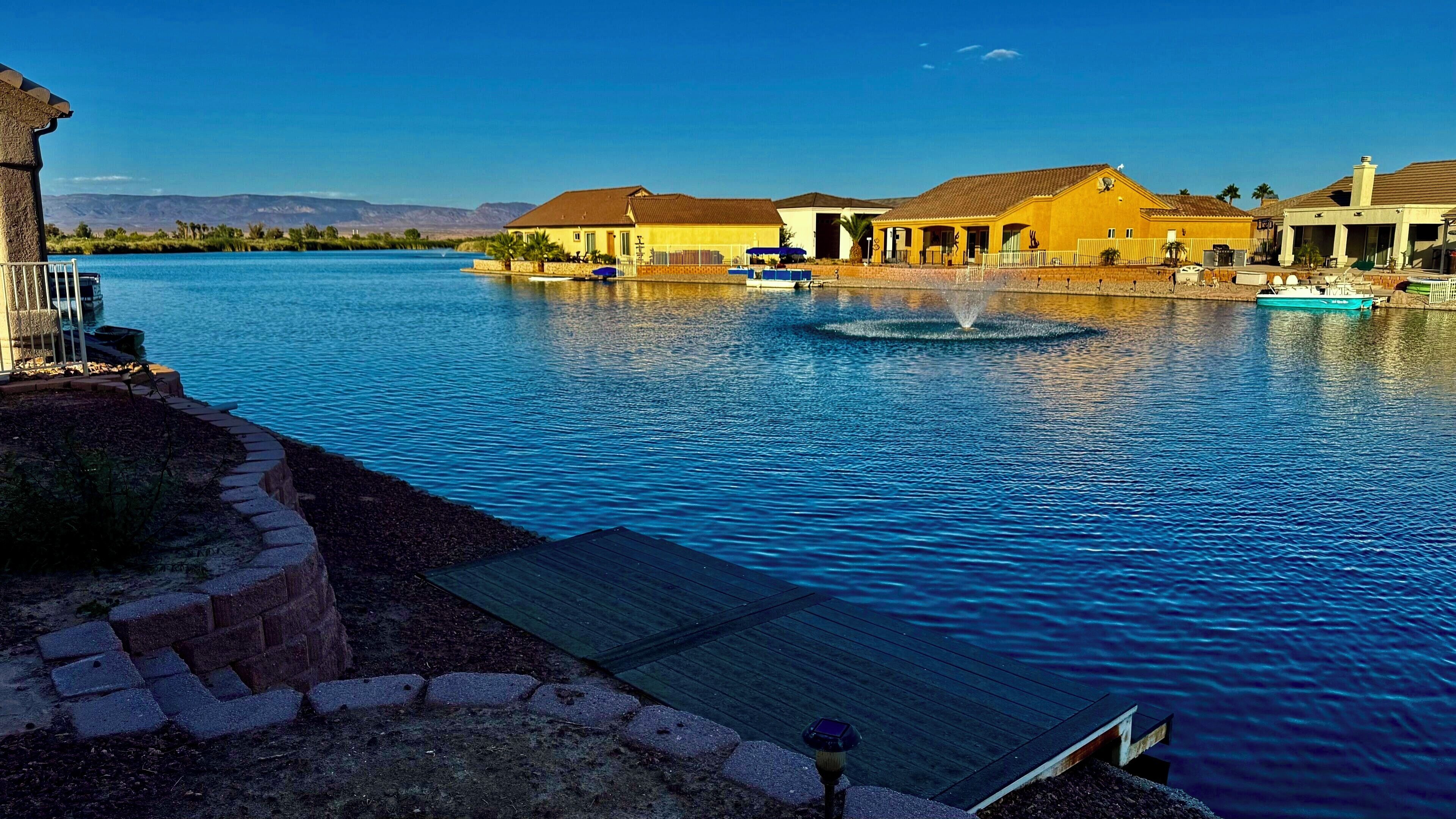 A waterfront property with a dock, a fountain, and several buildings with yellow and white exteriors.