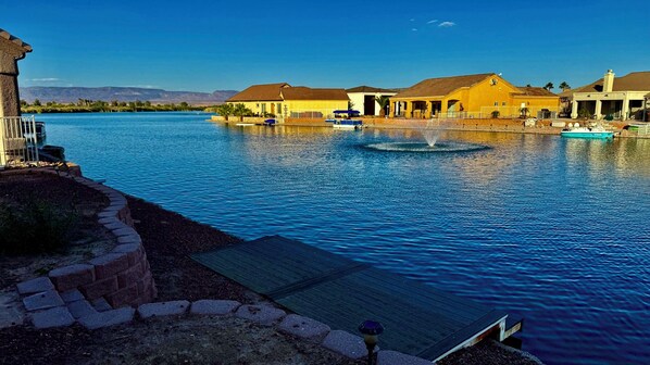 A waterfront property with a dock, a fountain, and several buildings with yellow and white exteriors.