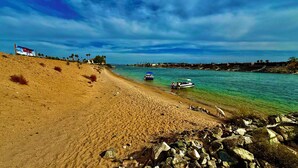 Ein Strand mit klarem türkisblauem Wasser, ein Boot in der Nähe des Ufers und ein Schild im Hintergrund.
