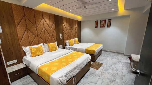 A hotel room with two beds, wooden headboard panels, marble flooring, and a ceiling fan.