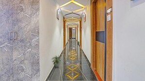 A hotel hallway with a marble floor, geometric ceiling design, and a door labeled "101".