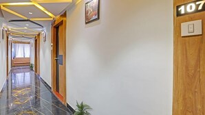 A hotel hallway with a polished black floor, wooden doors, and a number sign indicating room 107.
