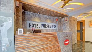 A reception desk with a marble wall, a sign reading "HOTEL PURPLE ICON", and a QR code.