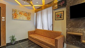 A modern lobby with a sofa, a ceiling fan, a clock, and artwork on the walls.