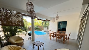 Une terrasse avec des meubles en osier, une piscine et un coin repas.