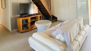 Une chambre à coucher moderne avec un grand lit, un escalier en bois, une télévision et un fauteuil en osier.