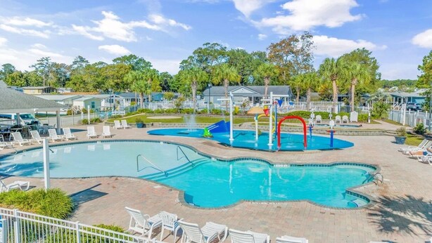 A swimming pool with multiple lanes, a water slide, and lounge chairs. - Oceanside Village Beautiful 3BR 3BA - Golf Cart Included! (Surfside Beach)
