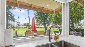 A kitchen with a large window overlooking a golf course. - The Palmer! Monterey Country Club, Hole 6, Resort Amenities! Golf cart included! (Palm Desert)