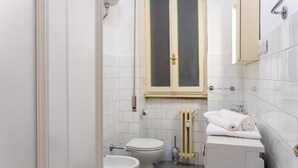 A small, clean bathroom with a toilet, bidet, and a sink. - Charming studio in  Roma with AC, WiFi, WASHING MACHINE for upto 3 person. (Roma)