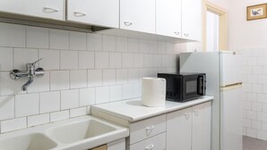 A kitchen with white cabinets, a sink, a microwave, and a refrigerator. - Charming studio in  Roma with AC, WiFi, WASHING MACHINE for upto 3 person. (Roma)